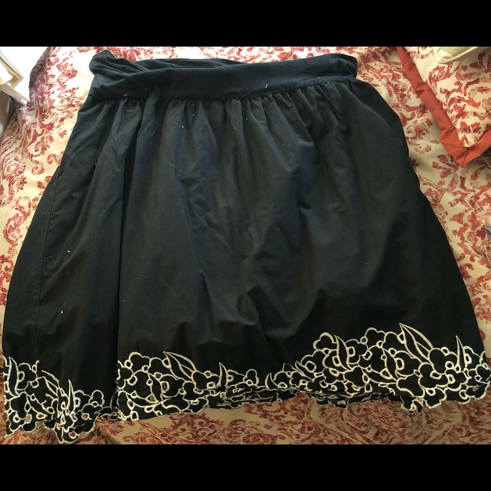 Black skirt with white embroidered flowers on it.